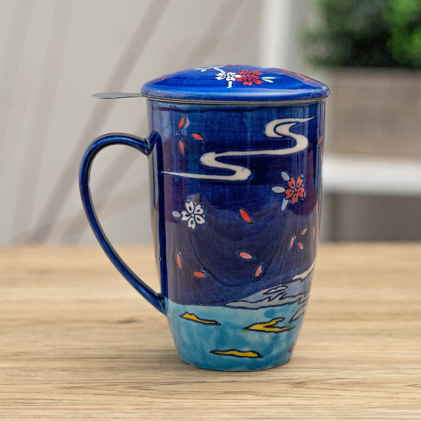 Blue ceramic mug with floral designs on a wooden surface