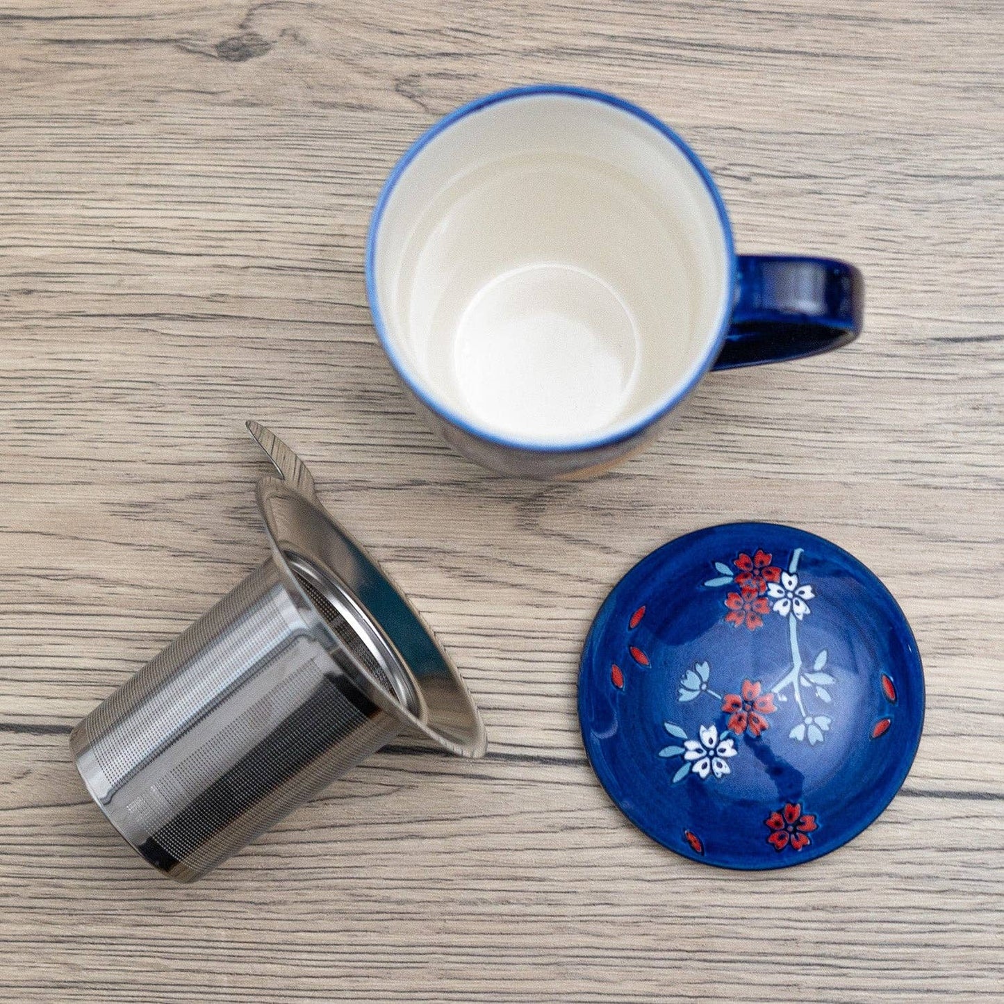 Blue mug with floral lid and metal filter on a wooden surface