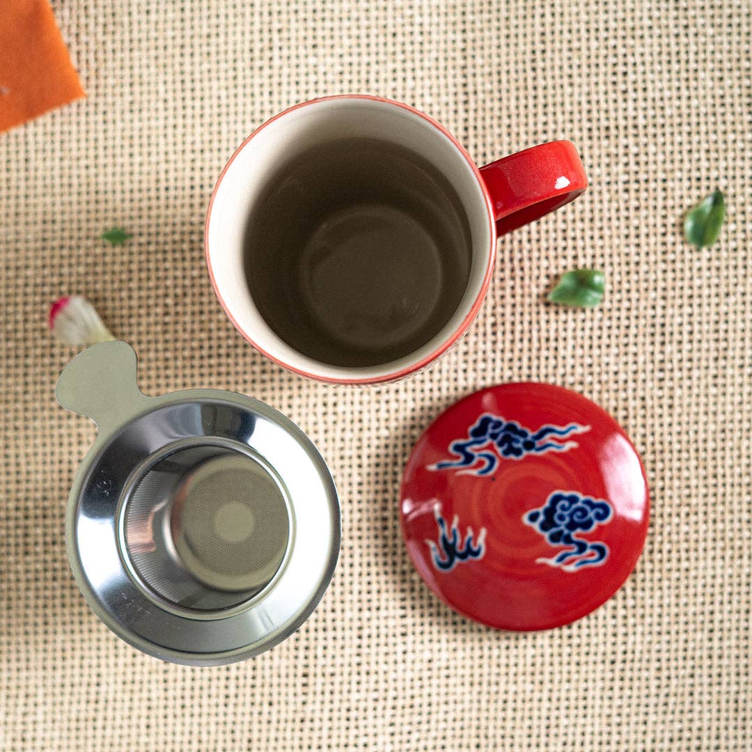 Red mug with a metal filter and decorative lid on a textured surface