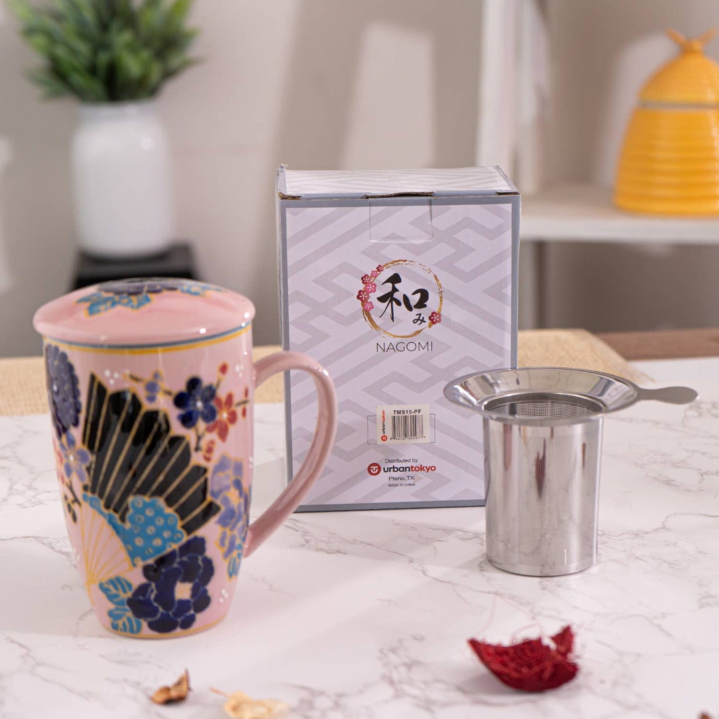 Decorative mug with floral design, Nagomi box, and metal cup on a marble surface.