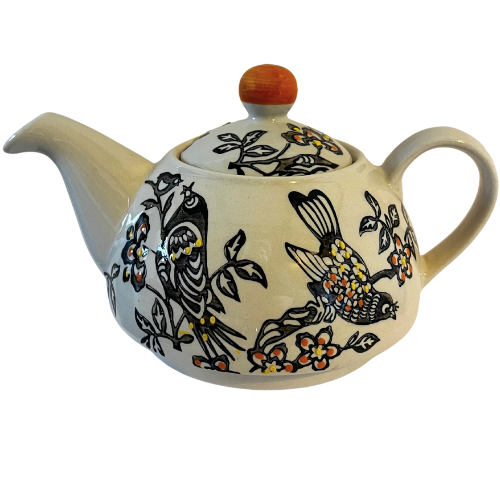 Ceramic teapot with bird and floral design on a white background