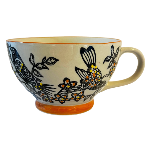 Ceramic mug with bird and floral design on a white background