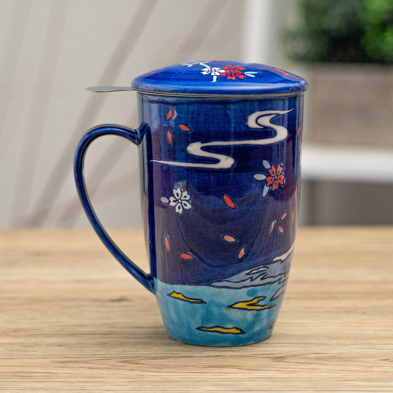 Blue ceramic mug with floral designs on a wooden surface