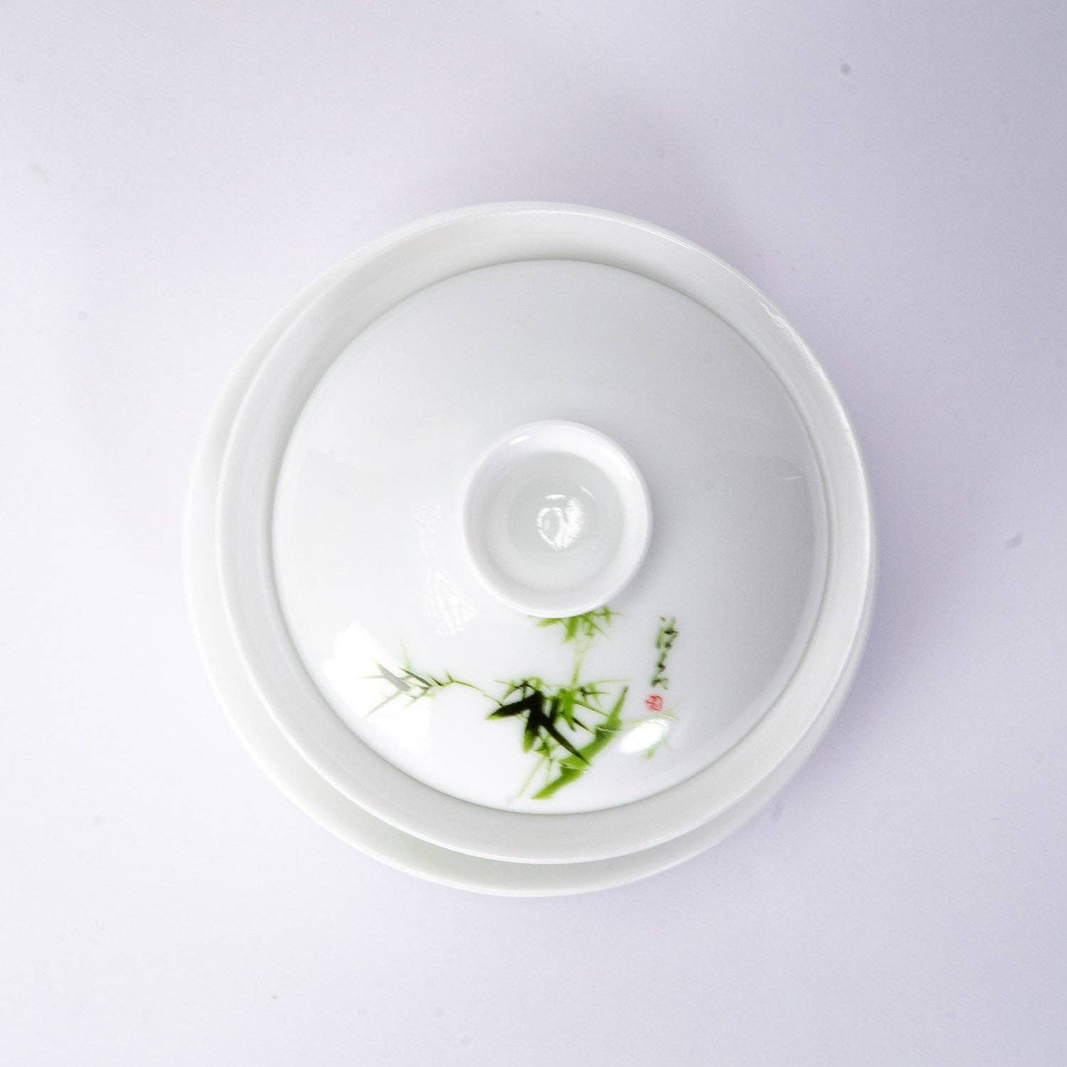White ceramic dish with green leaf design on a light gray background