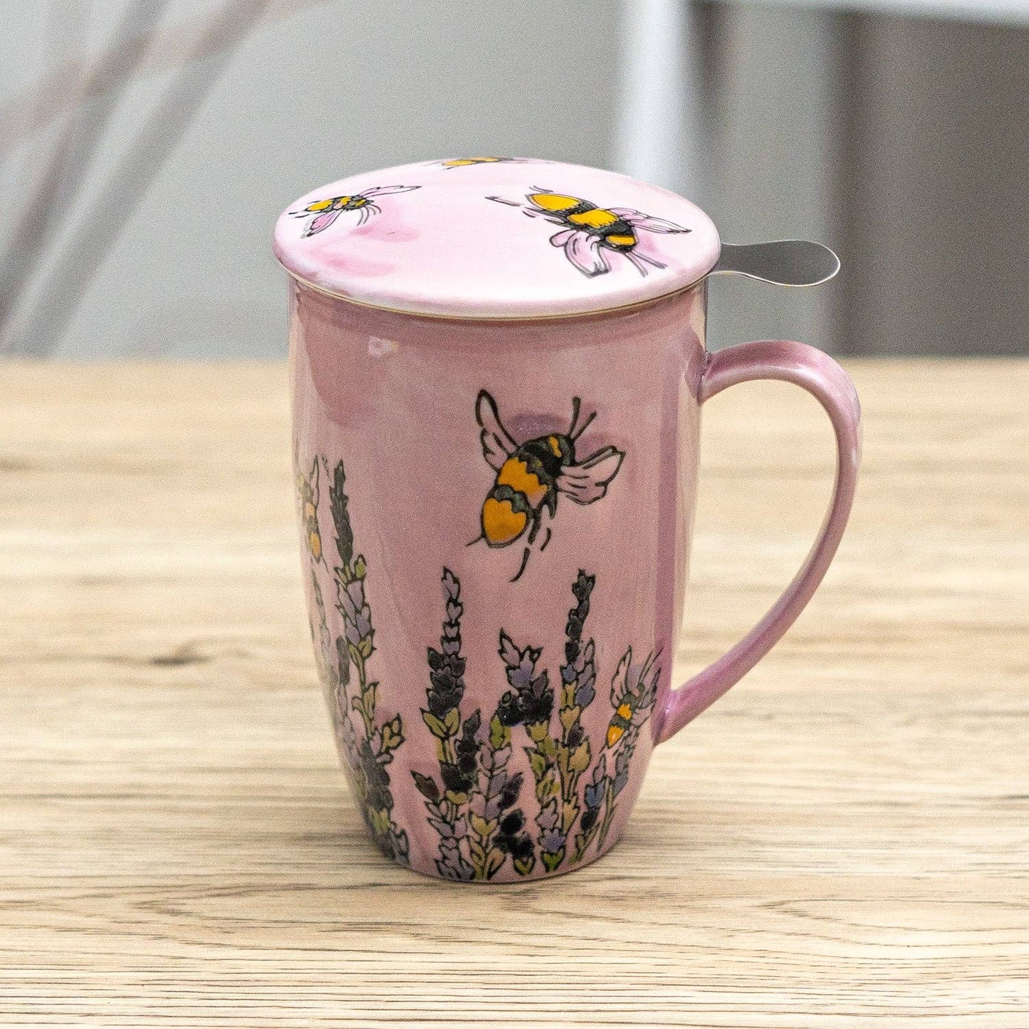 Pink mug with bee and lavender design on a wooden surface