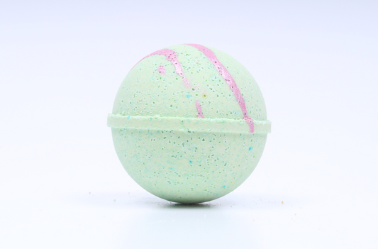 A spherical bath bomb with a speckled mint green texture, decorated with pink swirls and tiny multicolored glitter, shown on a clean white background.