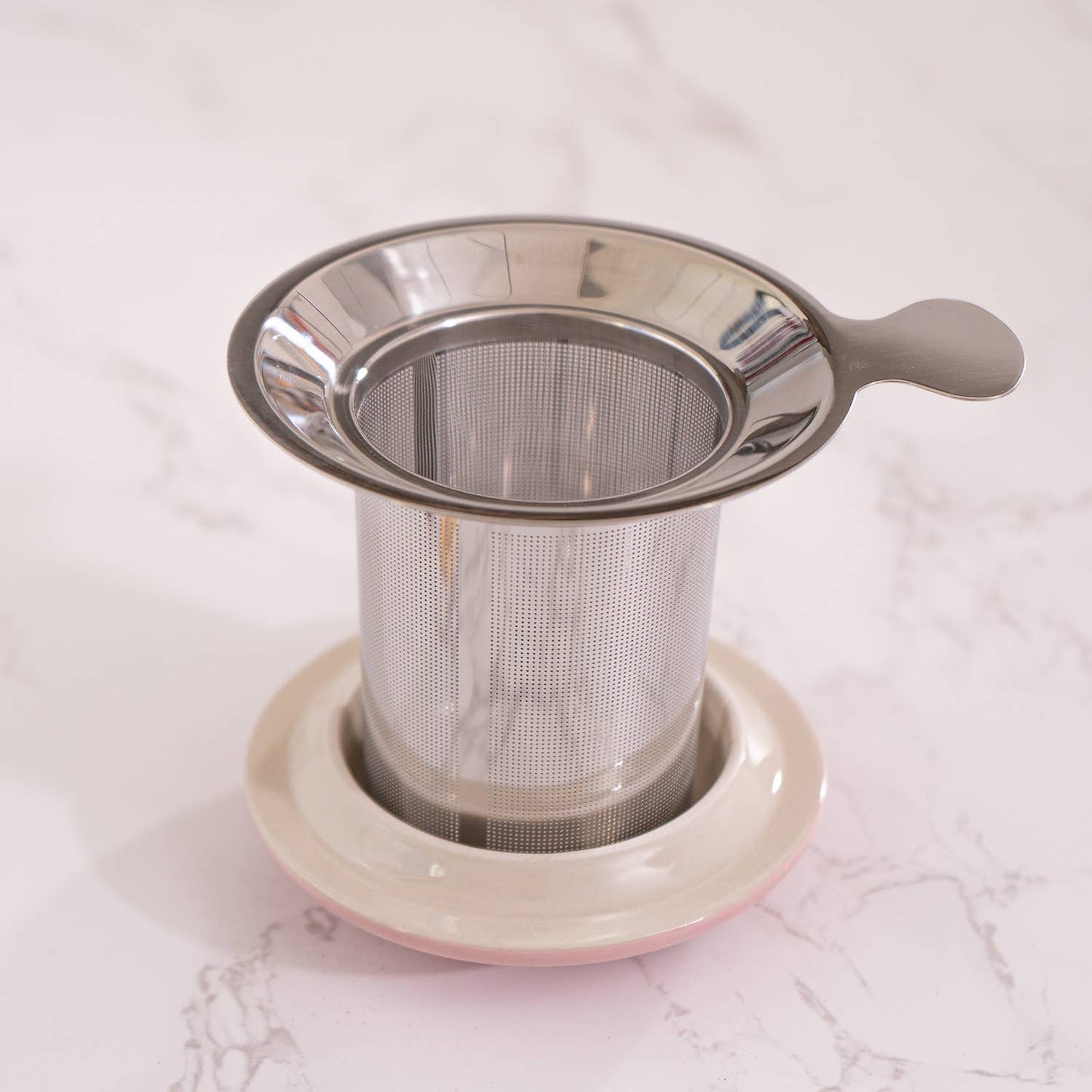 Metal tea infuser on a white marble surface