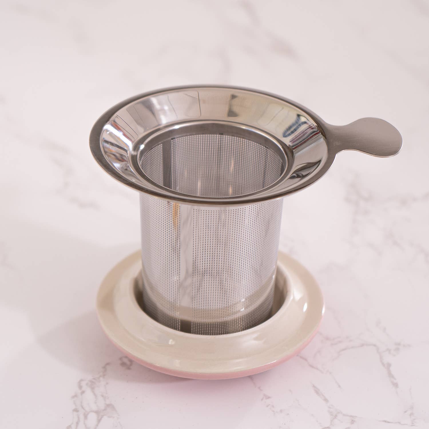 Metal tea infuser on a white marble surface