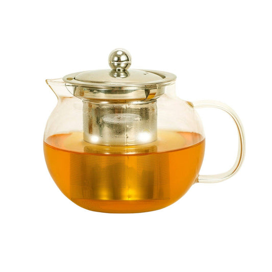 Clear glass teapot with metal lid and handle filled with tea on a white background