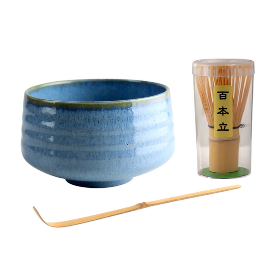 Blue ceramic bowl with wooden whisk and container on a white background