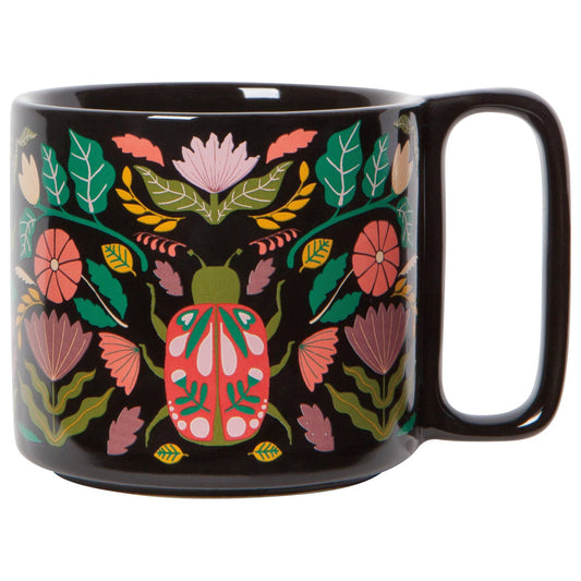 Black mug with colorful floral and beetle design on a white background