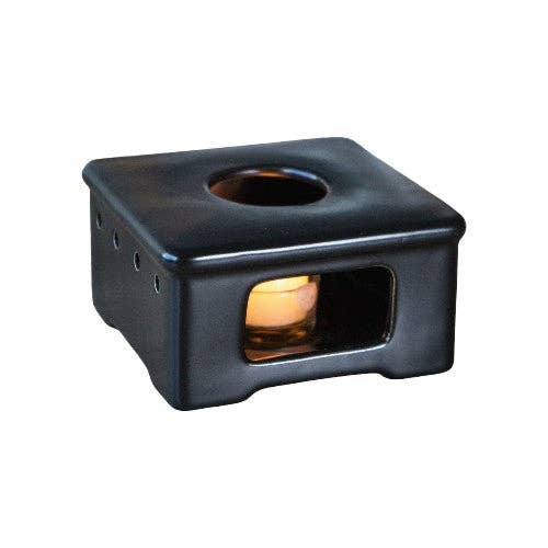 Black square wax warmer with a small candle inside on a white background